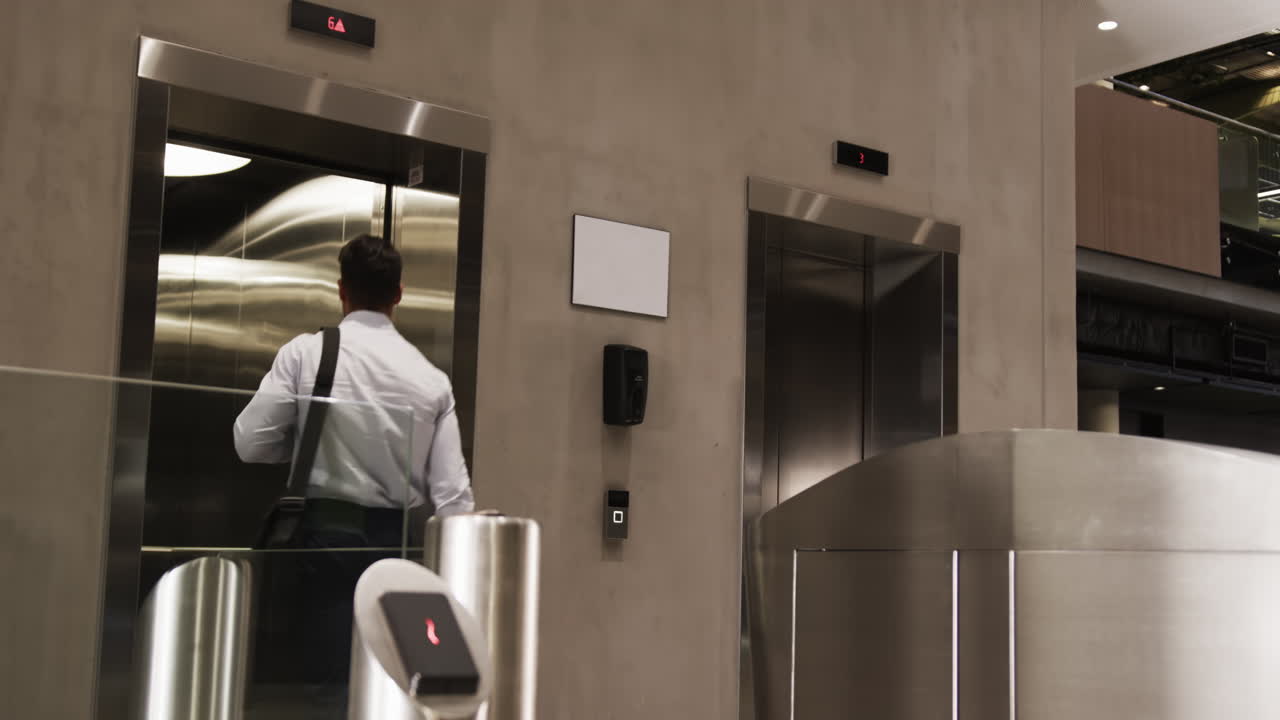 Entering elevator, businessman with shoulder bag going to office in modern building