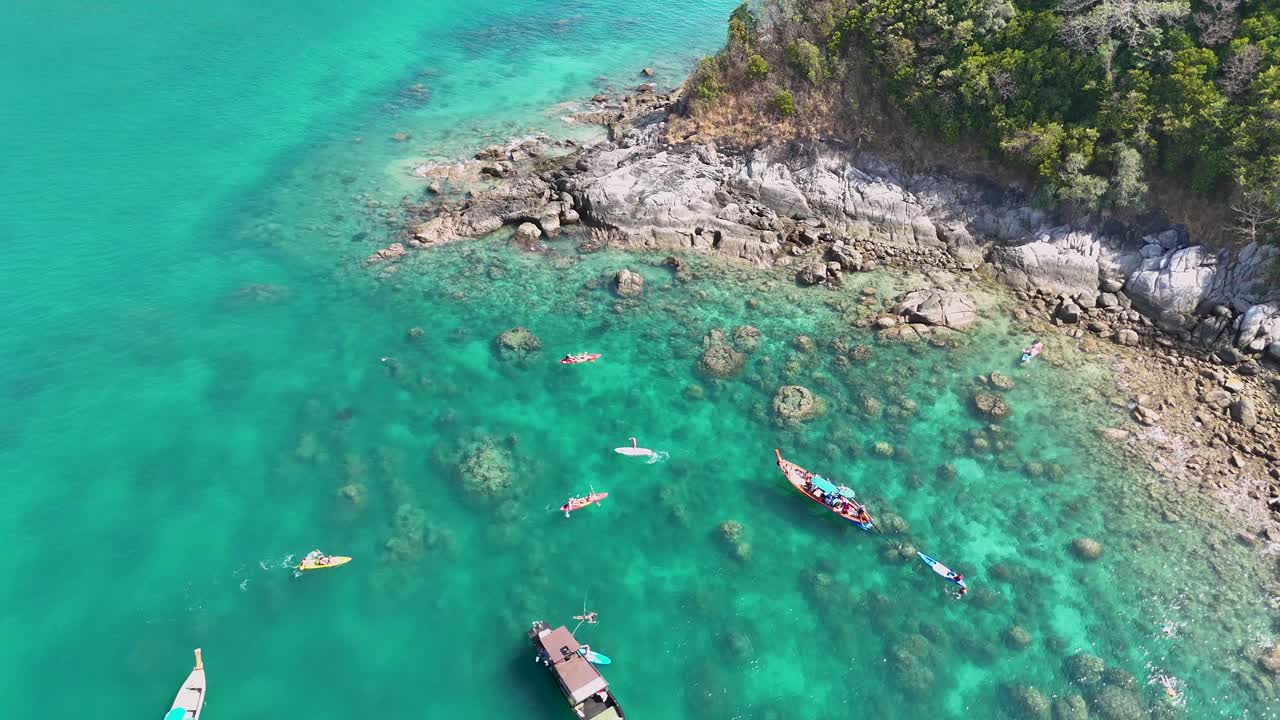 태국 푸켓 의 바위 가 있는 해안 근처 의 은 푸르키즈색 물 을 밝은 낮 에 탐험 하고 있는 카야크 타는 사람 들 의 공중 사진