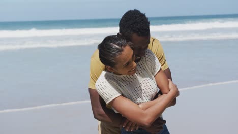 feliz pareja afroamericana abrazándose y abrazándose en la playa