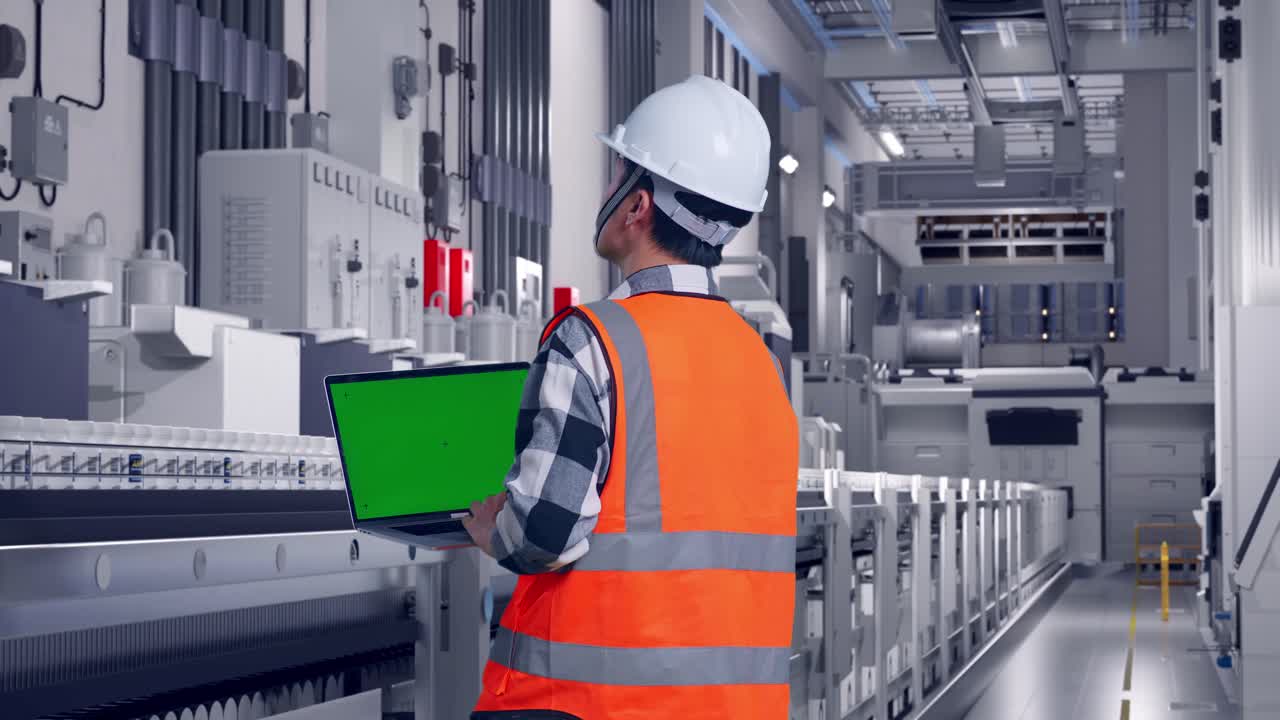 Back View Of Asian Male Engineer With Safety Helmet Working On A Green Screen Laptop And Looking Around While Standing At Pharmaceutical Factory, Vaccine Production Facility
