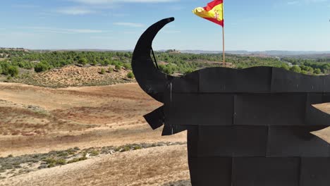 Aerial-view-of-the-head-of-a-huge-black-bull-billboard-with-the-spanish-flag-in-its-head