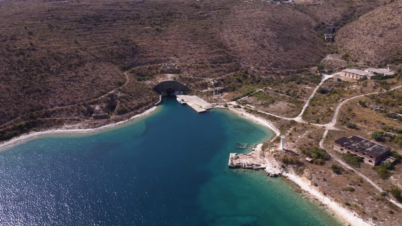 toma aérea en órbita de una playa turquesa con estructuras comunistas abandonadas en la riviera albanesa
