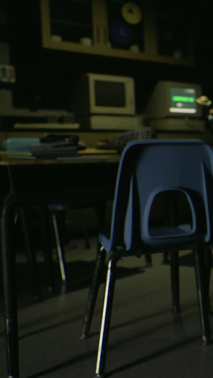 Empty classroom with chairs and old computers in low light settings