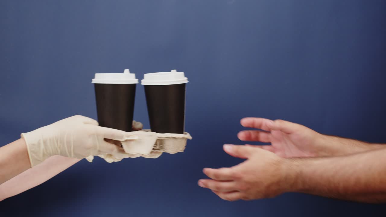 Hands Exchanging Two Takeaway Coffee Cups in Holder