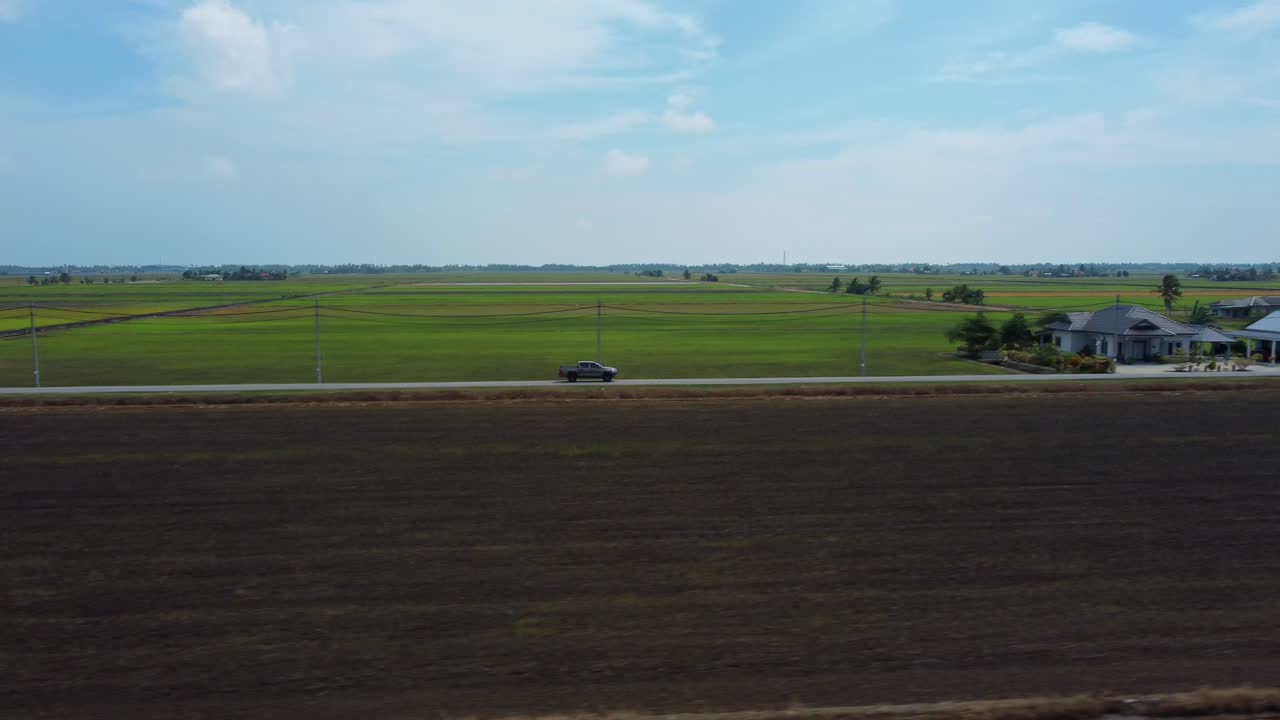 camioneta lateral seguir y revelar disparo de avión no tripulado rodeado de campos de arroz verdes