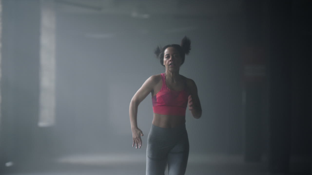 Athlete doing cardio workout in loft building. Female runner jogging in gym