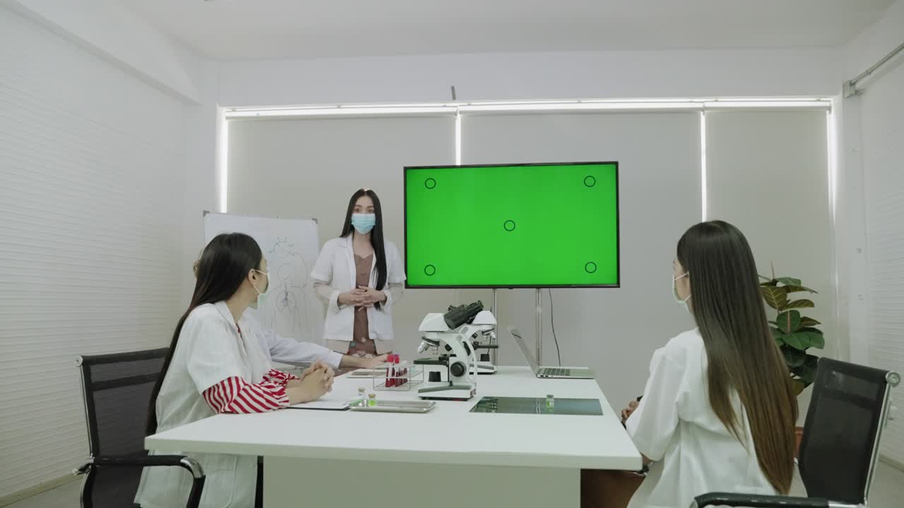 의사의 회의에서, 젊은 여자의 의사는 녹색 화면에서 그녀의 의학적 정보를 제시하고있었습니다.