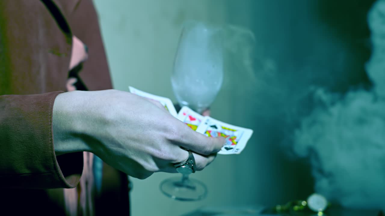 Una chiromante tiene in mano una tazza fumante e delle carte sopra un tavolo con gioielli misteriosi. Dietro le quinte. Vista laterale. Inquadratura cinematografica