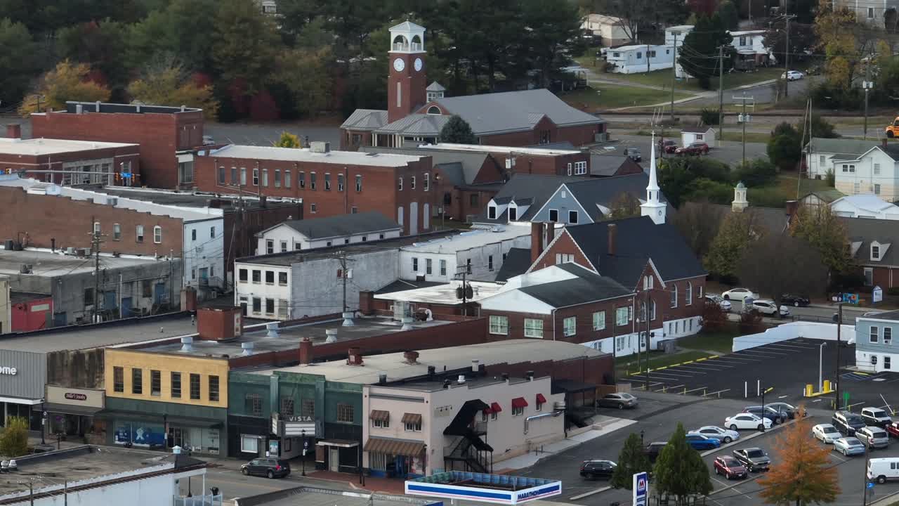 Aerial zoom shot of small town in america with stores and church in background. Cloudy autumn day with parking cars. Orbit shot. Connecticut, USA.