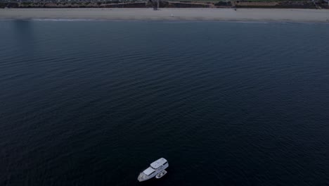 Eine-Wunderschöne-Drohnenaufnahme-Aus-Der-Luft,-Die-über-Ein-Weißes-Boot-In-Richtung-Küste-In-Long-Beach,-Kalifornien,-Fliegt