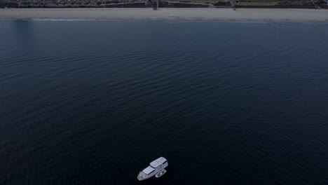 un hermoso dron aéreo revela una toma, volando sobre un bote blanco hacia la costa en long beach, california