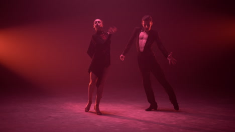 un hombre y una mujer magníficos bailando en un escenario iluminado. una pareja bailando.
