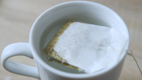 amazing close-up slow motion shot of a muy of hot water with a sachet of filtered chamomile resting in the water