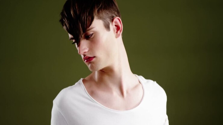 Androgynous man posing against green background