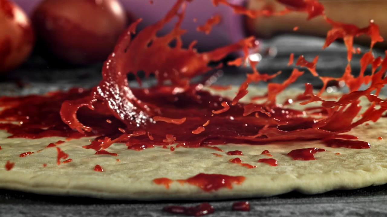 Schizzo al rallentatore di salsa rossa su impasto di pizza crudo