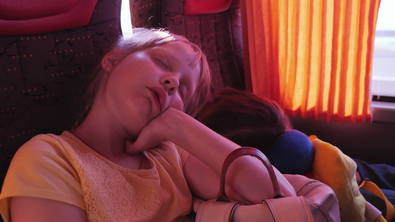 길에서 지친 두 소녀는 버스를 타고 서로 팔꿈치를 짚고 배낭을 메고 잠을 잔다