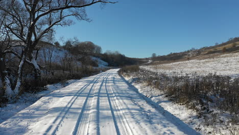 drone slowly flies over a road covered in snow