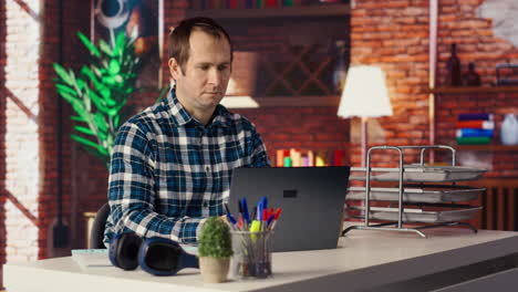 freelancer in home office sitting at desk and typing on laptop keyboard