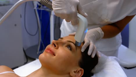 doctor performing laser hair removal on female patient face