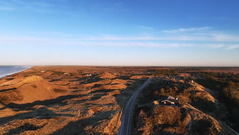 panoramic view houses are built between the sand dunes, and the dunes are illuminated by the yellow color of the sunset