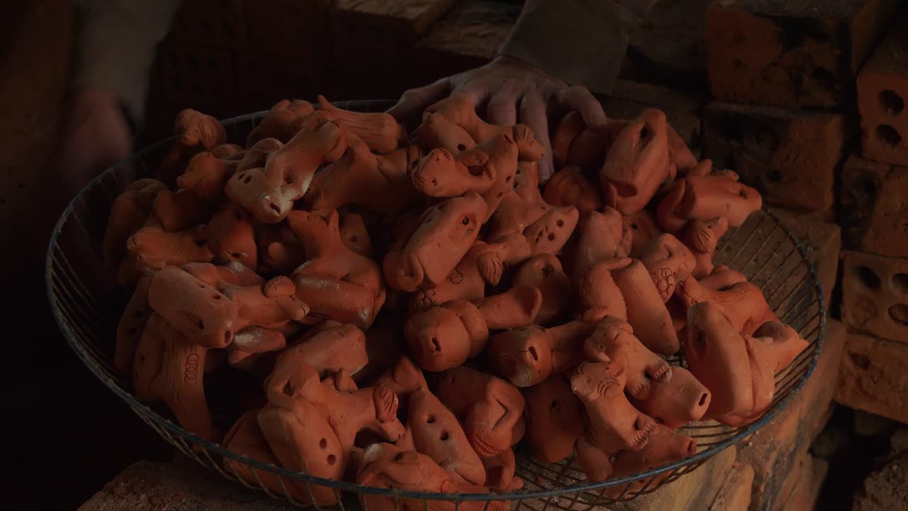 las flautas de arcilla recién cocidas y recolectadas a mano de un horno de leña en una canasta de metal muestran la artesanía tradicional y la expresión artística.