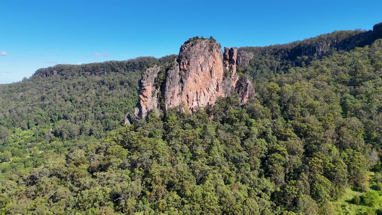 Drone footage captures the majestic rhyolite volcanic plugs of Nimbin Rocks under clear blue skies in lush Australian landscape