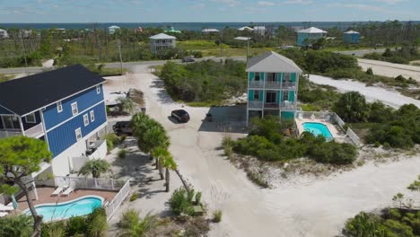 tomada de avión no tripulado de un vehículo que viaja por caminos de arena blanca pasando por condominios en cape san blas, florida