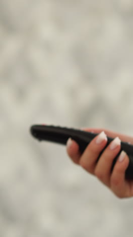 mujer sostiene el control remoto de la tv corriendo en casa. mujer atlética ve programas de televisión corriendo en la cinta de correr en la casa. atleta busca diversión durante el entrenamiento