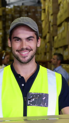 warehouse worker smiling at camera carrying a box