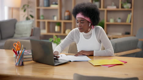 una mujer joven estudiando en su escritorio con una computadora portátil