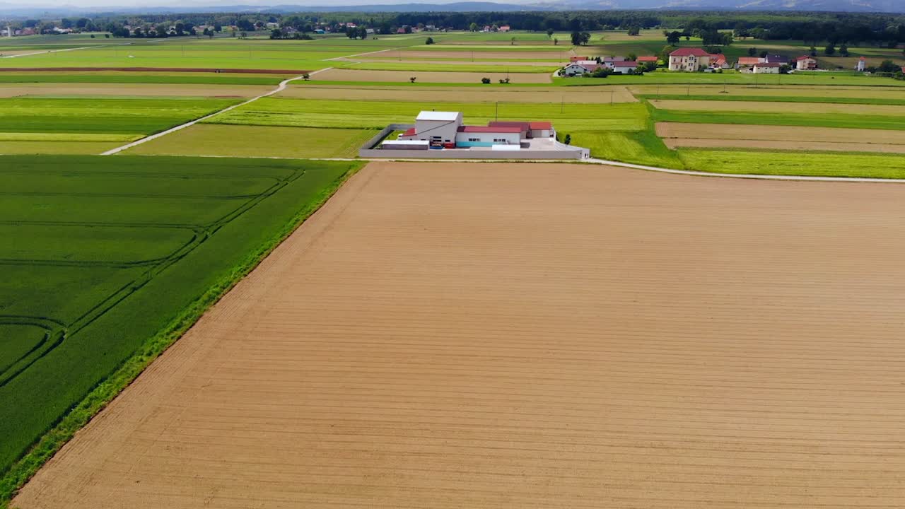 Luftdrone mot bygninger i frodig, grønt jordbruksland på landet