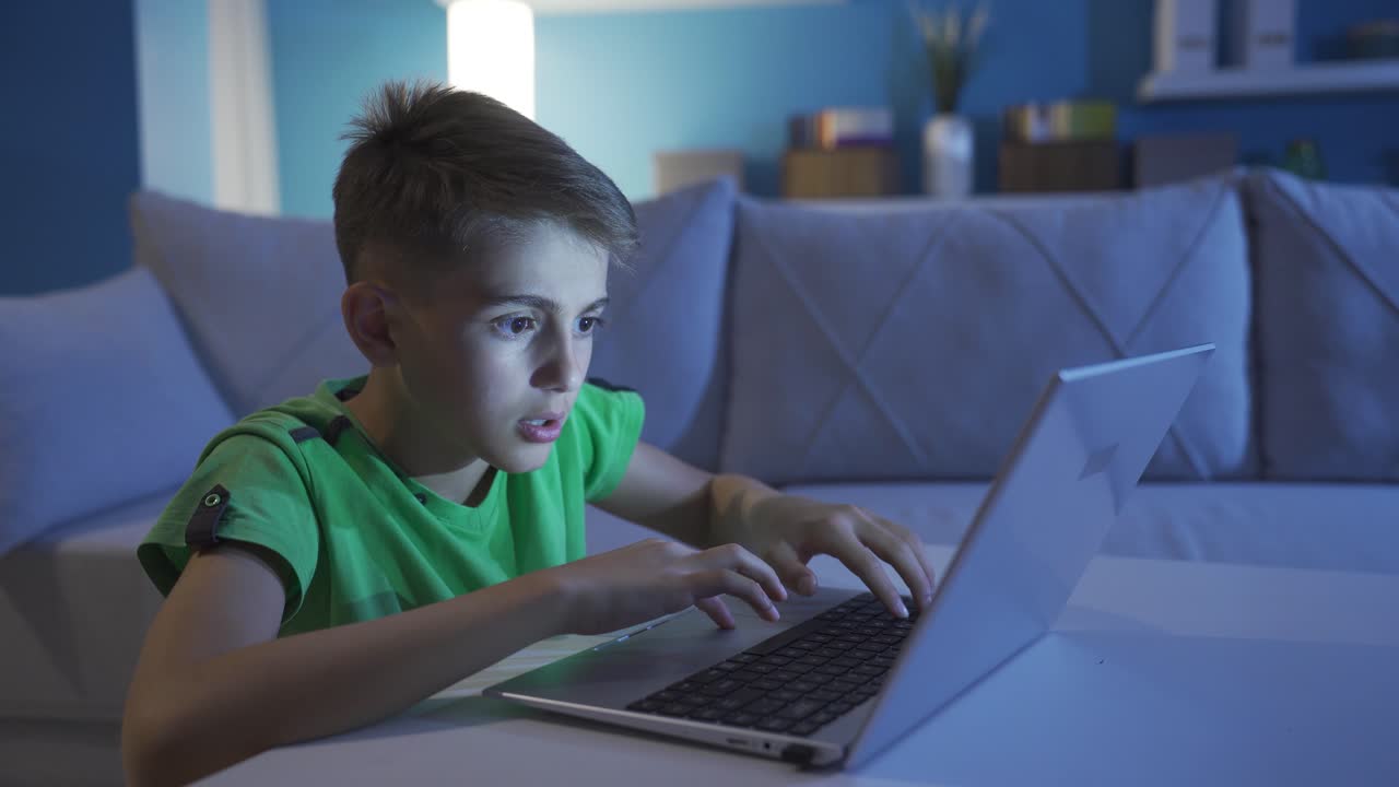 chico trabajando en la computadora portátil por la noche en casa.