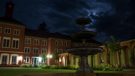 time lapse shot of old german psychiatry at night with fountain in foreground