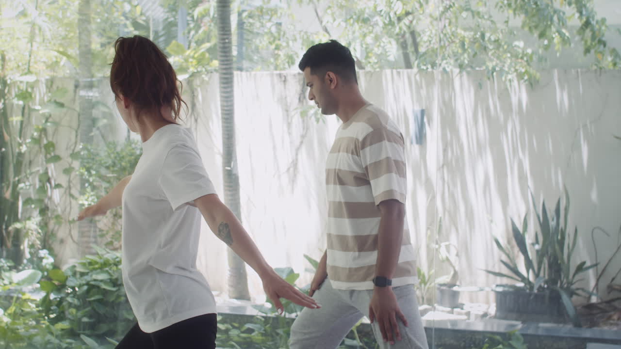 Woman Instructing Man Standing in Warrior Pose during Yoga Class