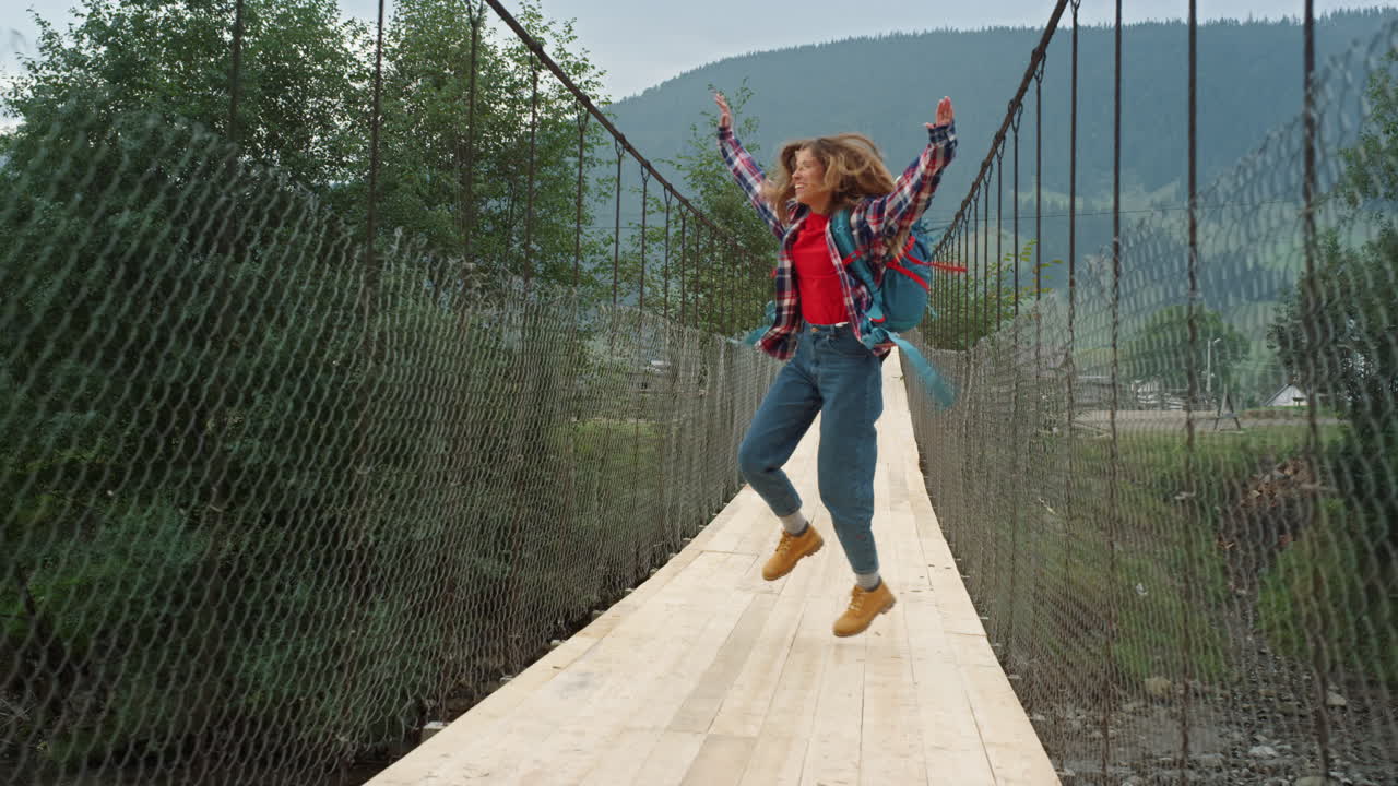 turista feliz corriendo por las montañas, el puente del río, una chica emocionada saltando en la naturaleza.
