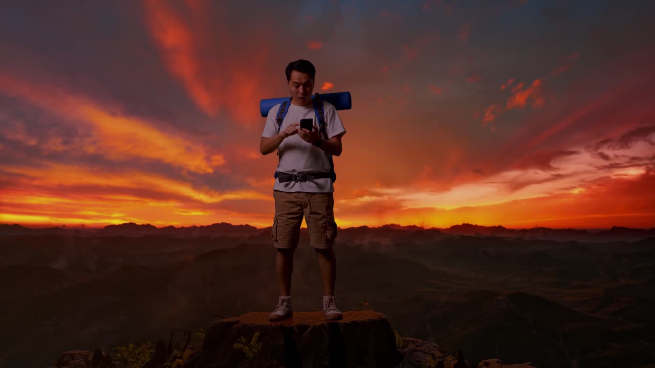 un excursionista feliz comprobando el teléfono en la cima de la montaña al atardecer