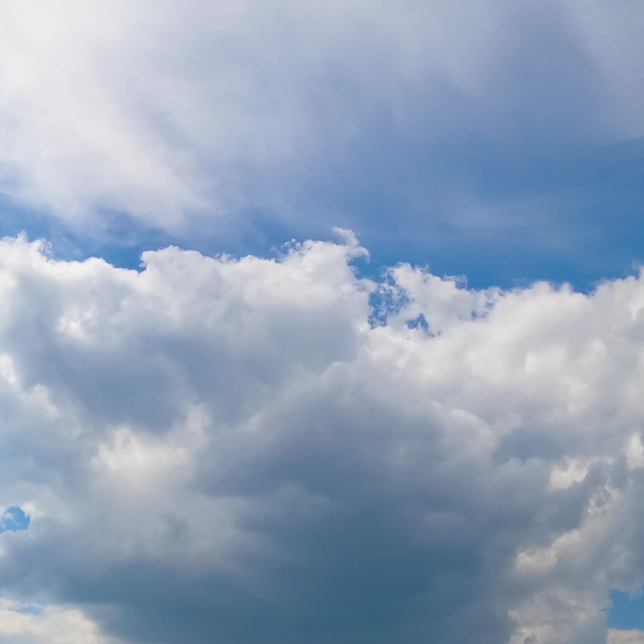 White cotton clouds soaring in the blue sky. Little clouds gathering into a big cloudscape. Timelapse