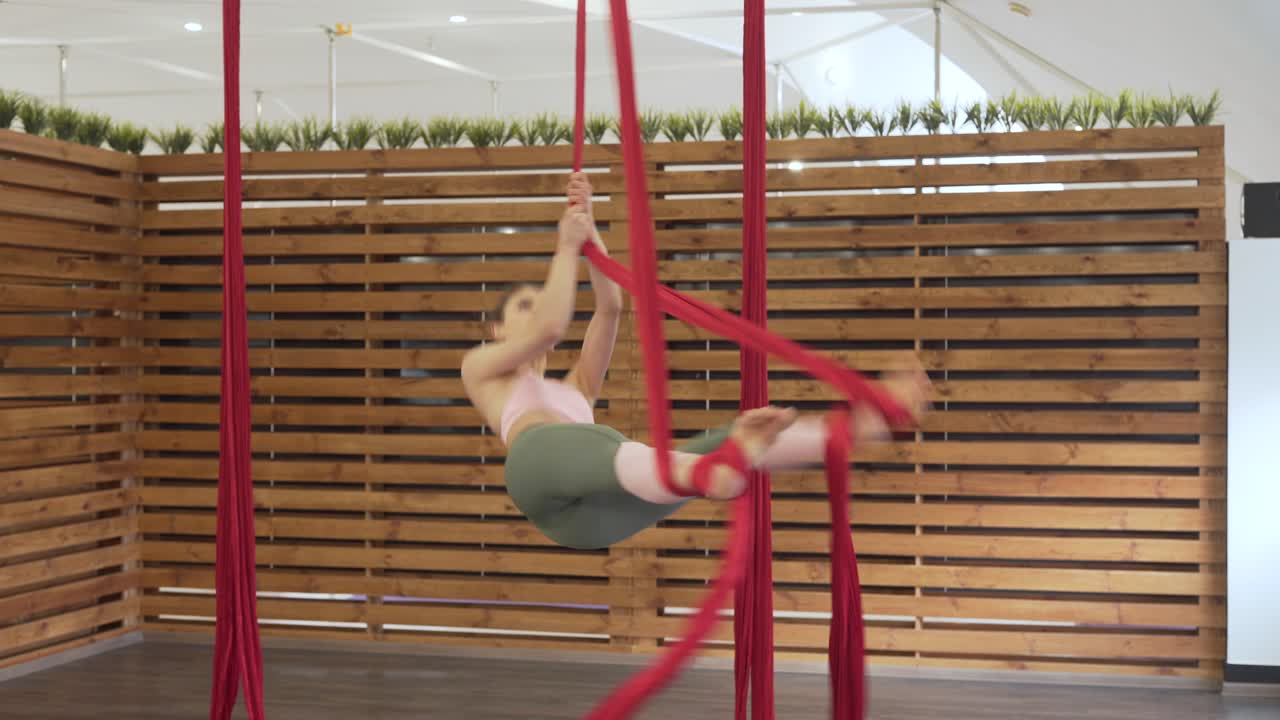 Bella ragazza atletica vestita con leggings aderenti e top rosa che pratica fly yoga-fitness
