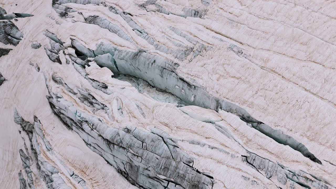 Aerial view of the rugged ice formations of Fellaria Glacier in Valmalenco, Alps. Camera tilts down to capture the cracks and crevices in the ancient ice