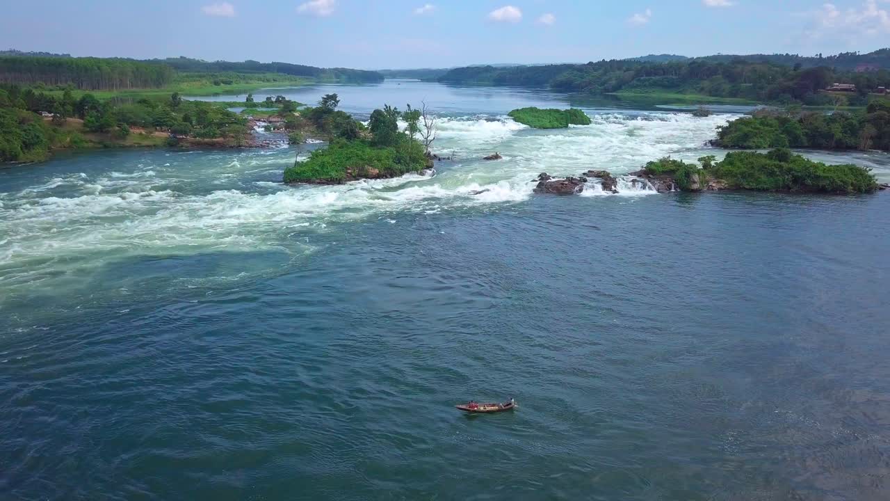 Aerial view of fishermen navigating the whitewater rapids of the Nile River in a traditional wooden boat, showcasing the power of nature and the resilience of local dangerous fishing practices