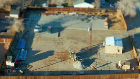 Backhoe loader spreads gravel at a construction site - miniature tilt shift effect time lapse