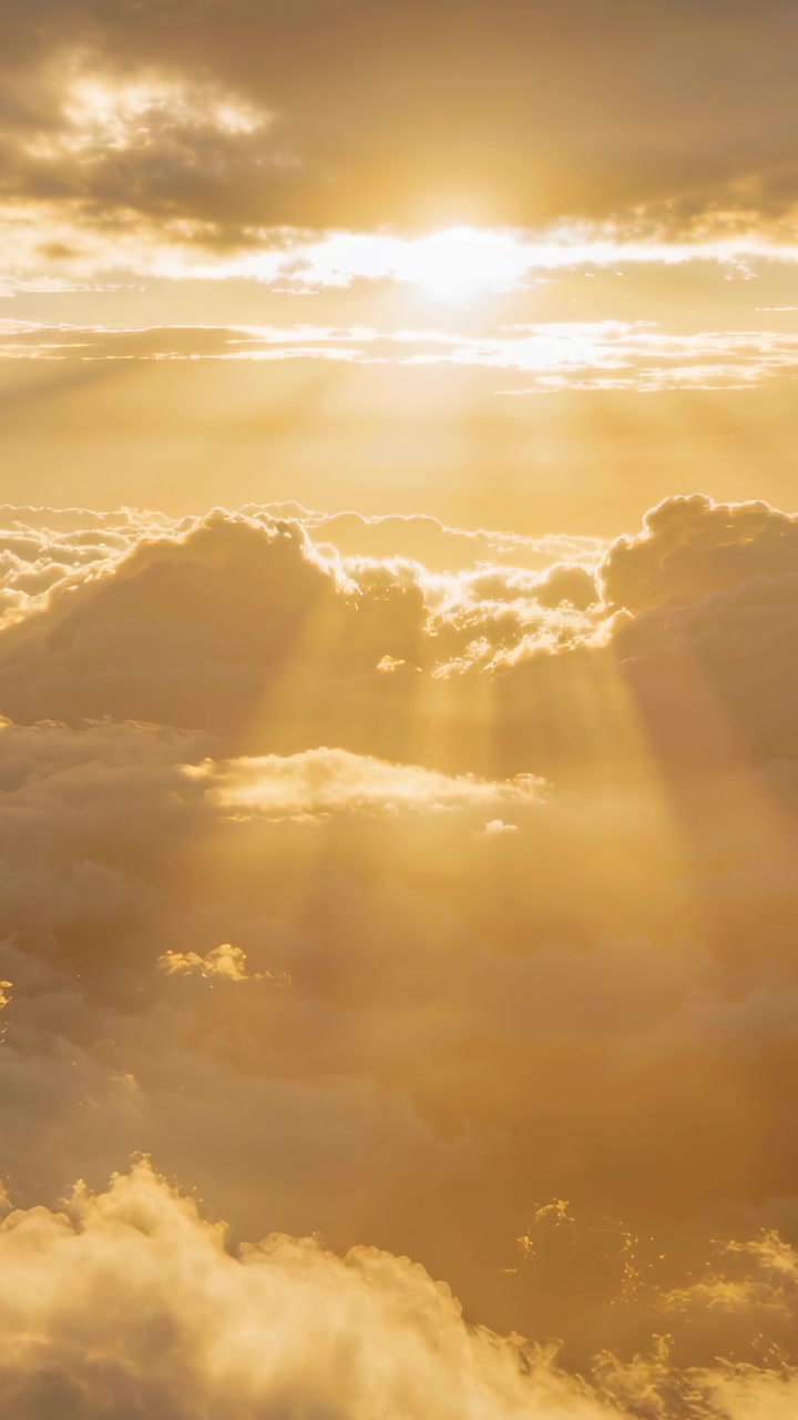 Vertical video: Brightening sun sending shifting rays across layered cloud deck at golden hour