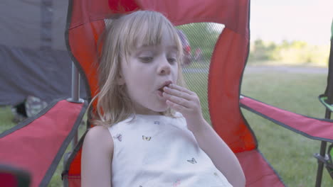 cute little girl eating a snack on a camping trip