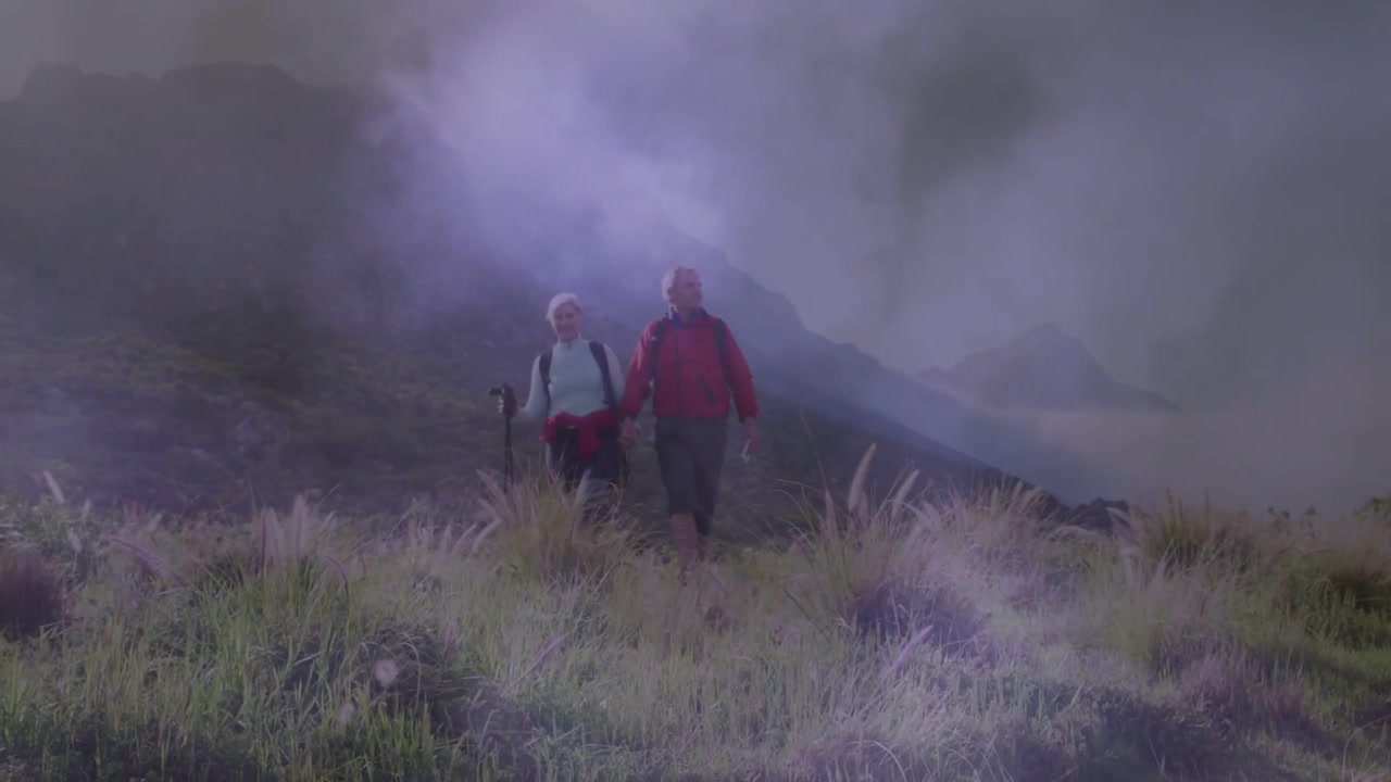 Inizio del clip: Escursionisti anziani scendono verso la telecamera per la salute, con nebbia viola che si avvolge attorno a un palo.