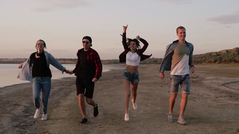 Gruppe-Von-Freunden,-Die-Glücklich-Zusammen-Am-Strand-Laufen