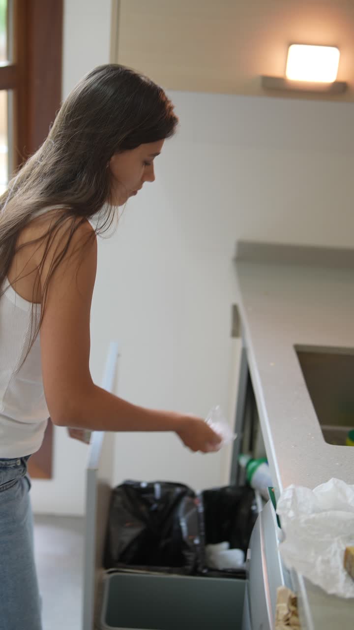 mujer arrojando basura a la basura en una cocina moderna