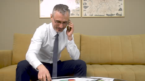 hombre feliz teniendo una conversación por teléfono y leyendo documentos