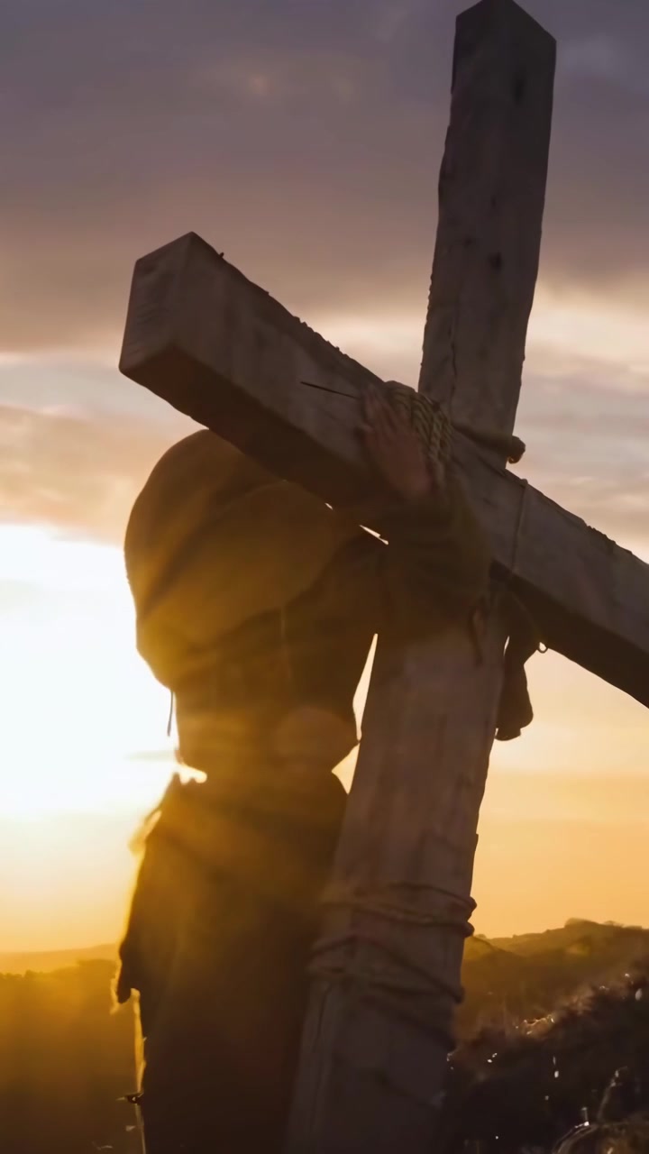 Silhouette di una persona che porta una croce di legno su per una collina al tramonto