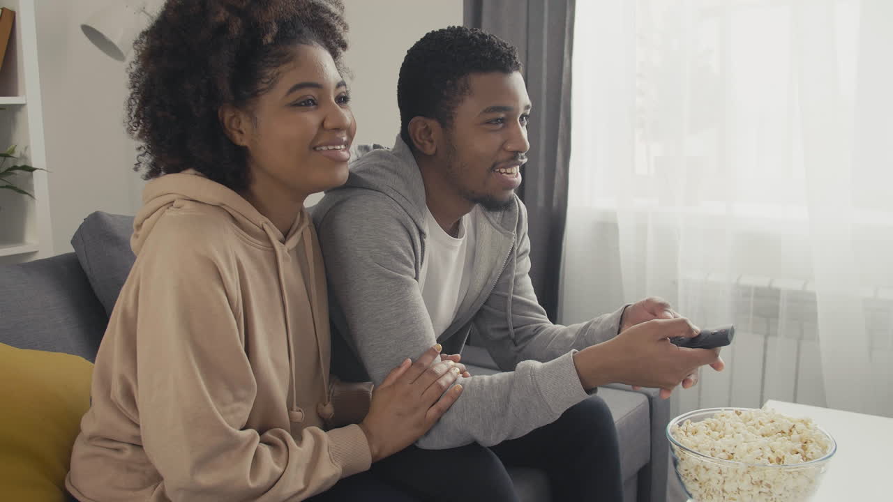Young Couple Choosing A Film With The Remote Control