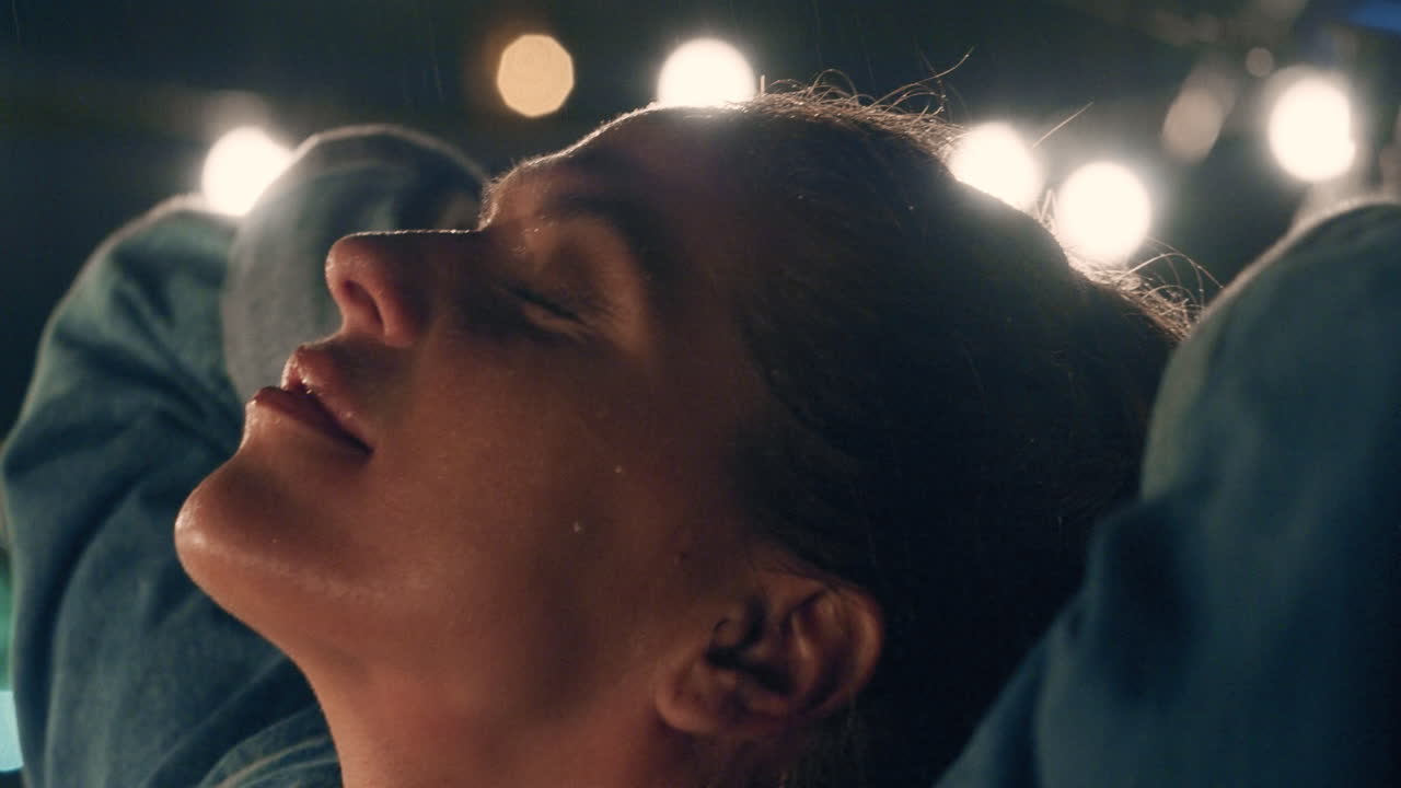 retrato de cerca de una hermosa mujer joven de pie bajo la lluvia disfrutando de las suaves gotas de lluvia tocando la piel emociones calmantes en cámara lenta